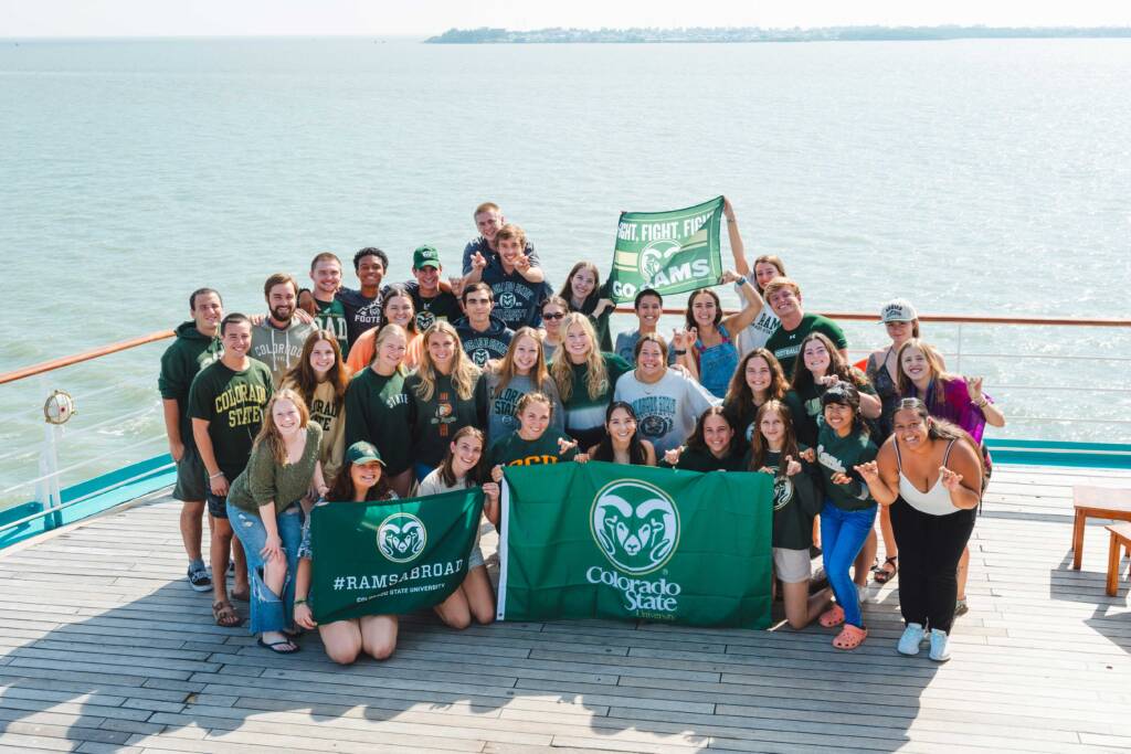 group of colorado state students on a dock together, holding up school flags